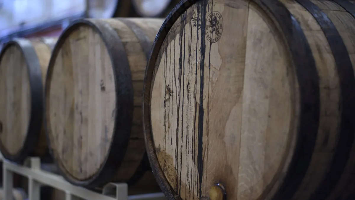 Close-up of wooden wine barrels used for fermentation and storage in a winery cellar.