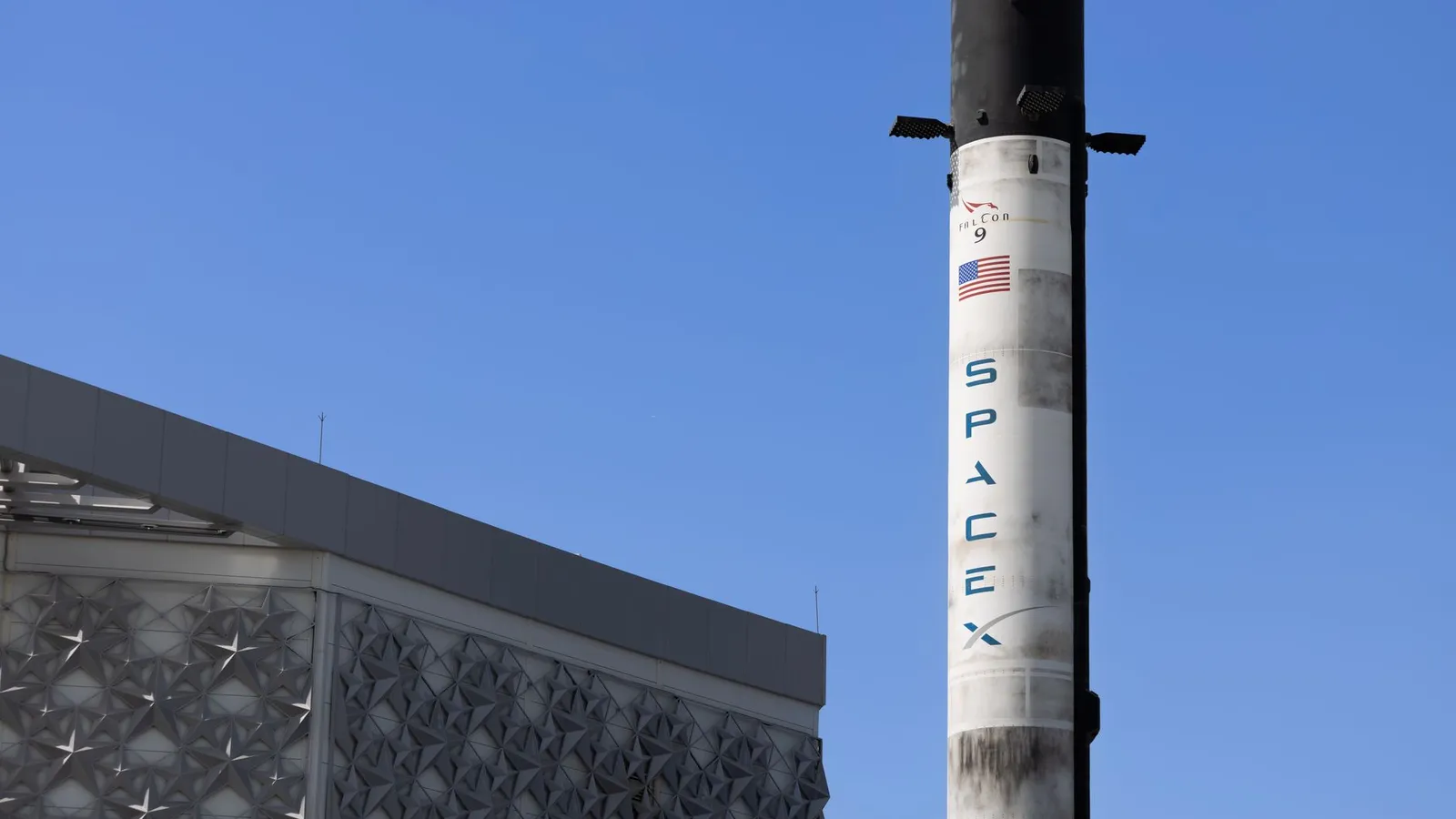 A SpaceX Falcon 9 rocket displayed outdoors against a clear blue sky in Dubai.