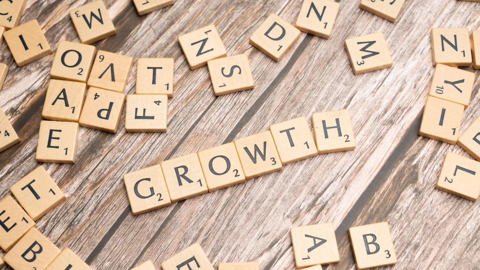 Scrabble tiles spelling 'growth' on a wooden surface symbolize progress and expansion.