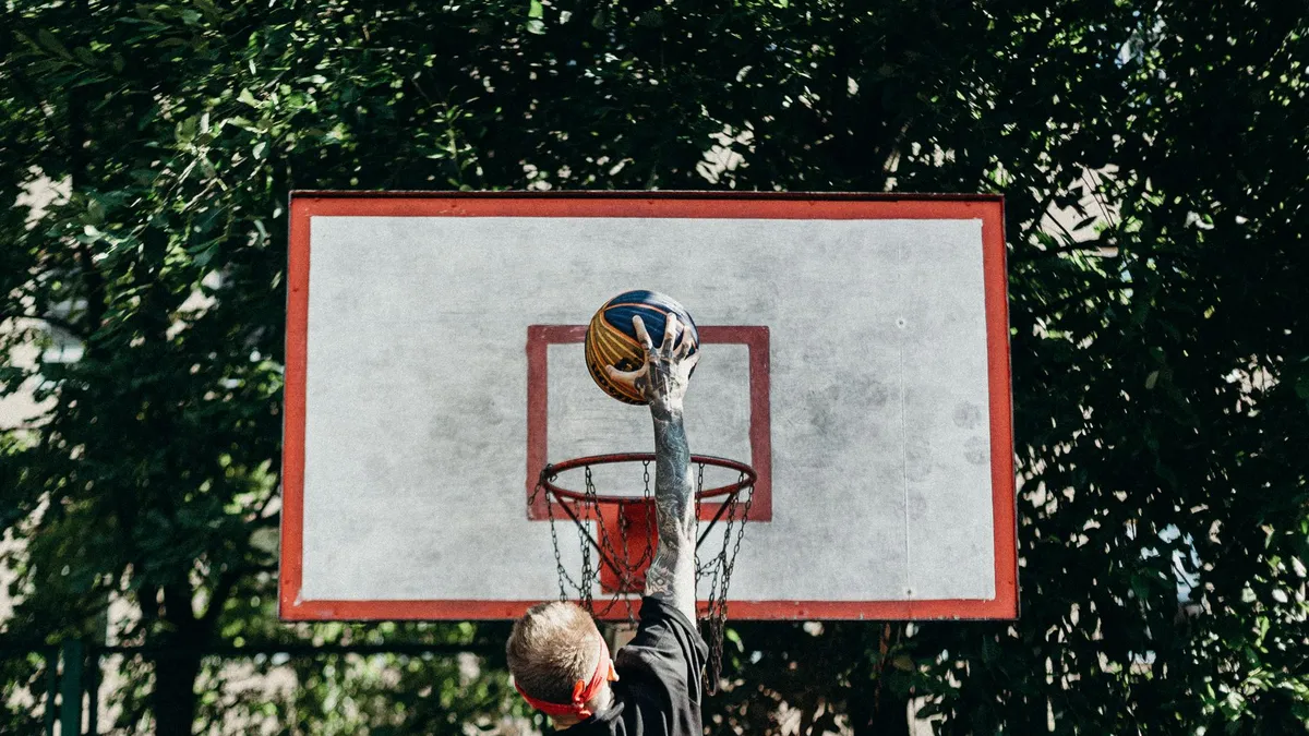 A man jumps to dunk a basketball outdoors, displaying athletic energy and skill.