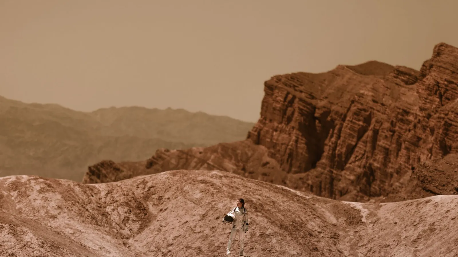 A woman astronaut stands on a barren, alien terrain, symbolizing space colonization.