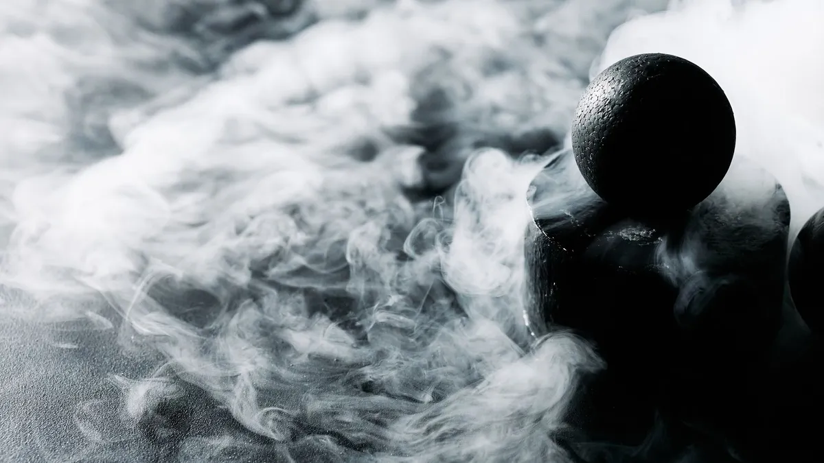 Mysterious black sphere enveloped in swirling smoke on a dark textured surface.