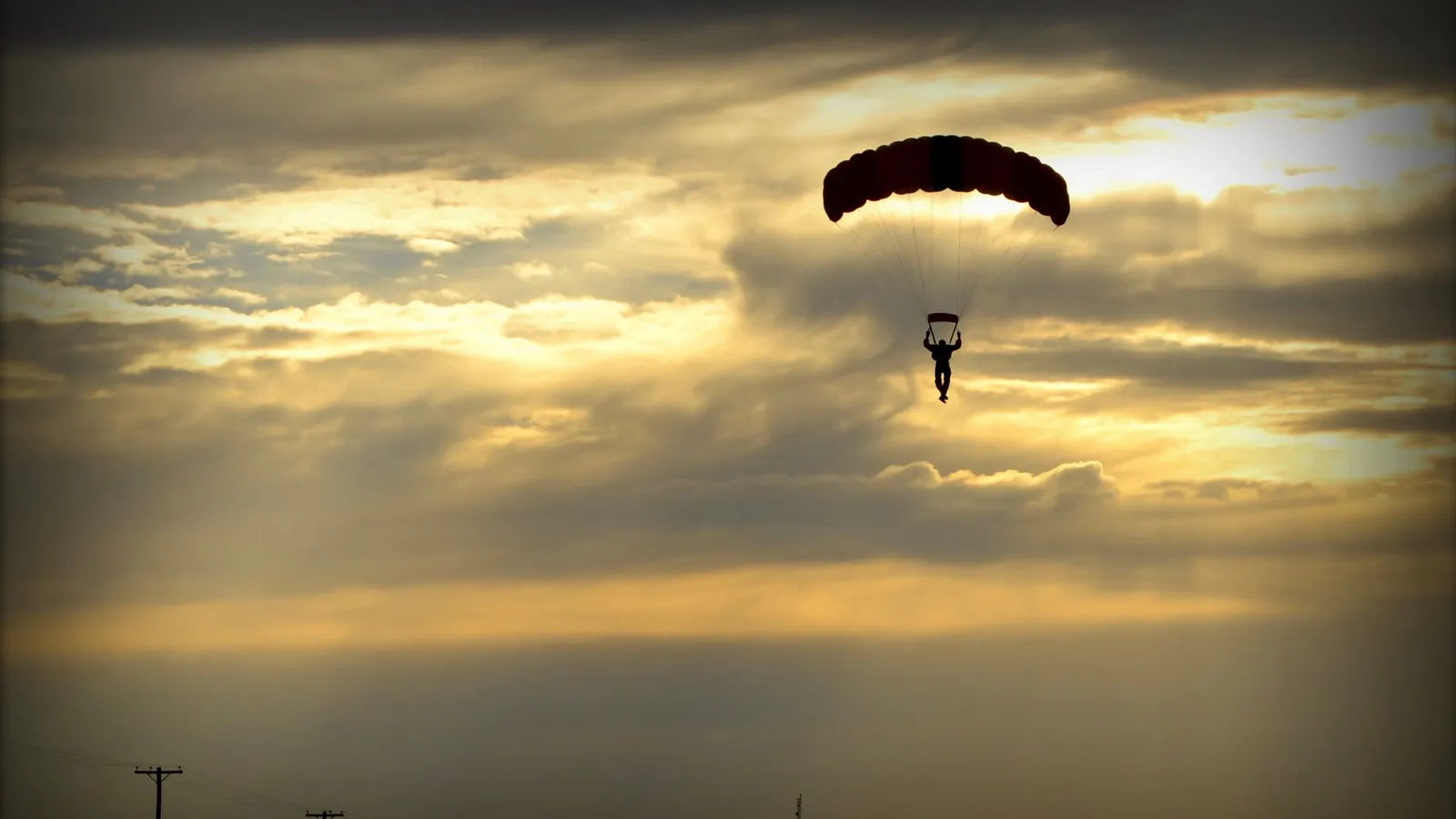 A scenic silhouette of a parachutist descending from a parachute against a dramatic sunset sky in Argentina. — Photo by maria Chaile on Pexels