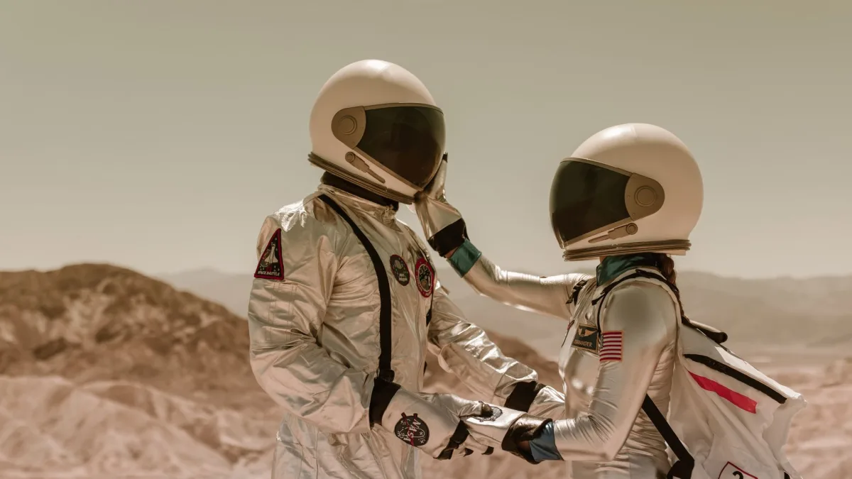 Two astronauts in space suits share a tender moment, face to face, in a desert setting. — Photo by RDNE Stock project on Pexels