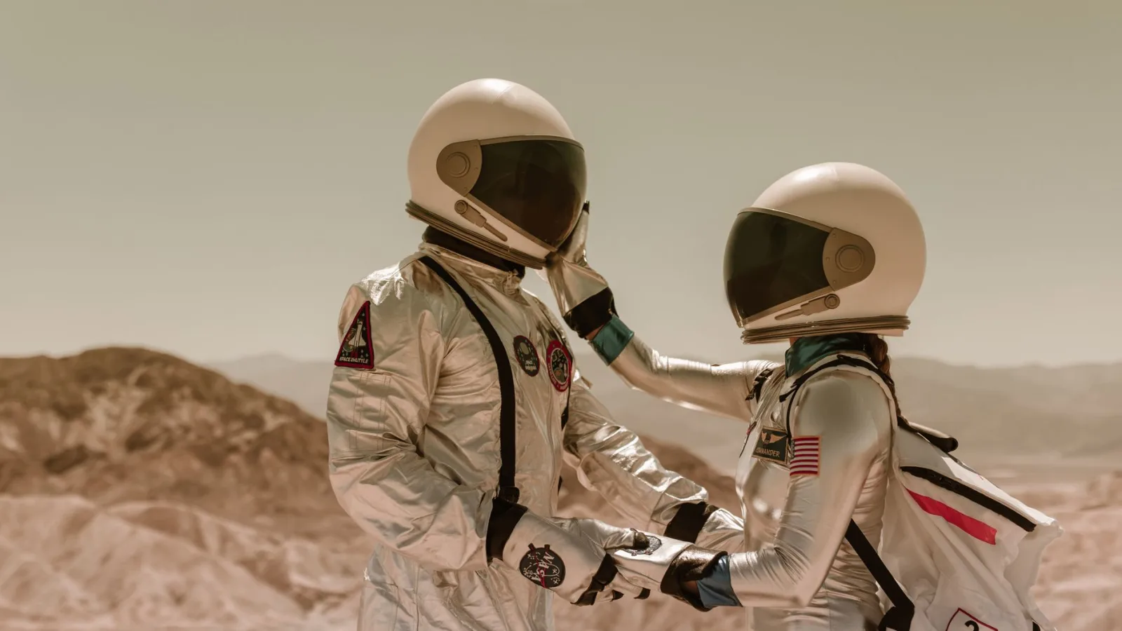 Two astronauts in space suits share a tender moment, face to face, in a desert setting. — Photo by RDNE Stock project on Pexels