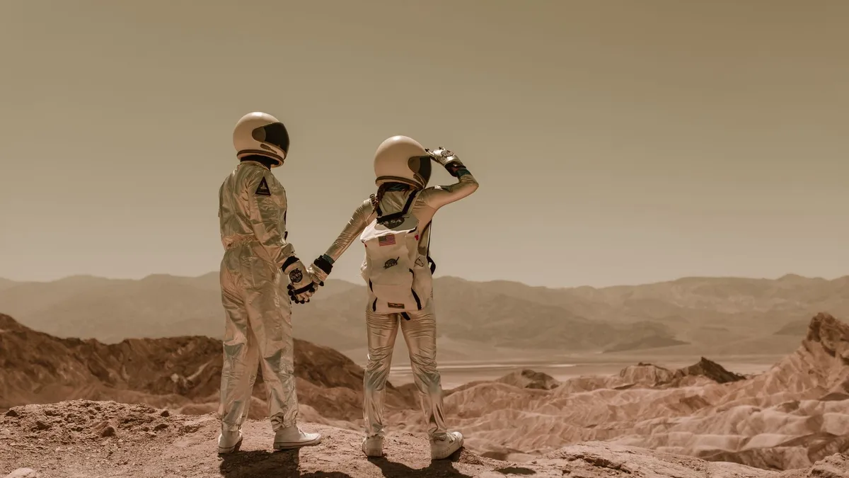 Two astronauts holding hands, exploring rocky Mars-like terrain. — Photo by RDNE Stock project on Pexels